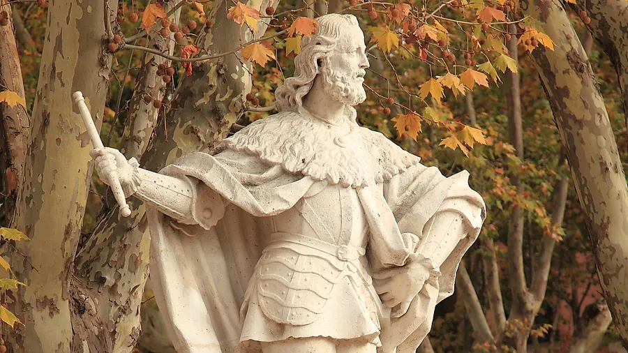 Estatua de piedra de Fernán González entre árboles con hojas de otoño en la Plaza de Oriente