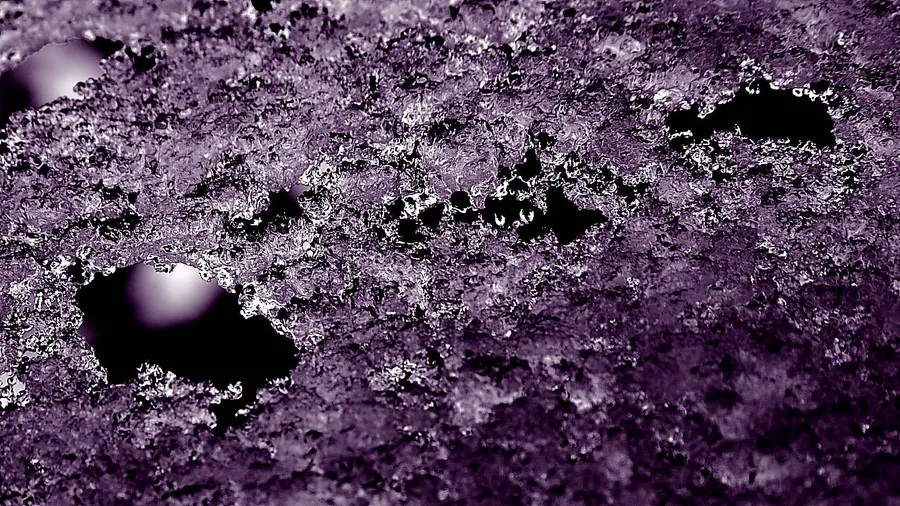 Primer plano de una capa de hielo con burbujas, en tonos morados