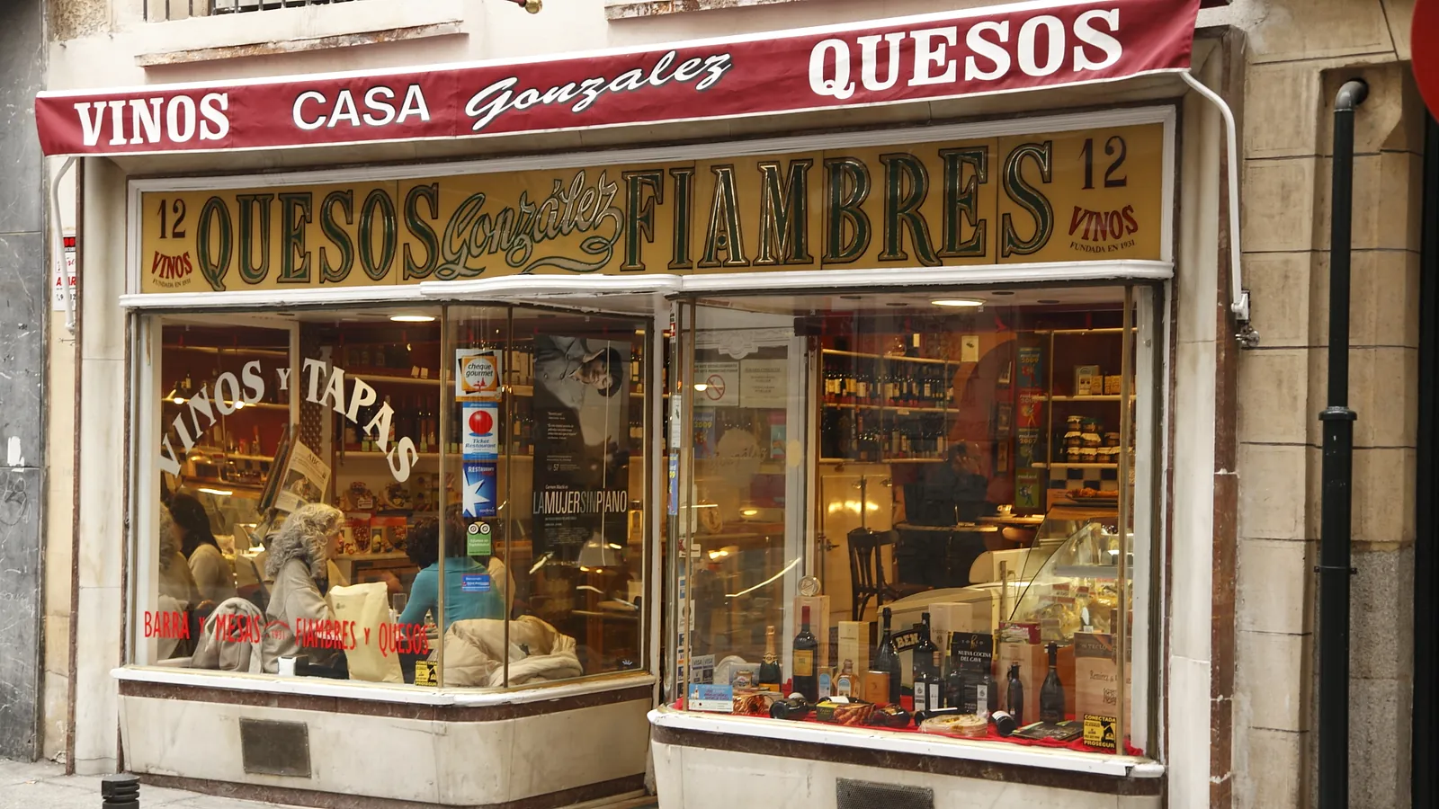 Escaparate de una tienda de quesos, fiambres y vinos con barra de tapas en Madrid