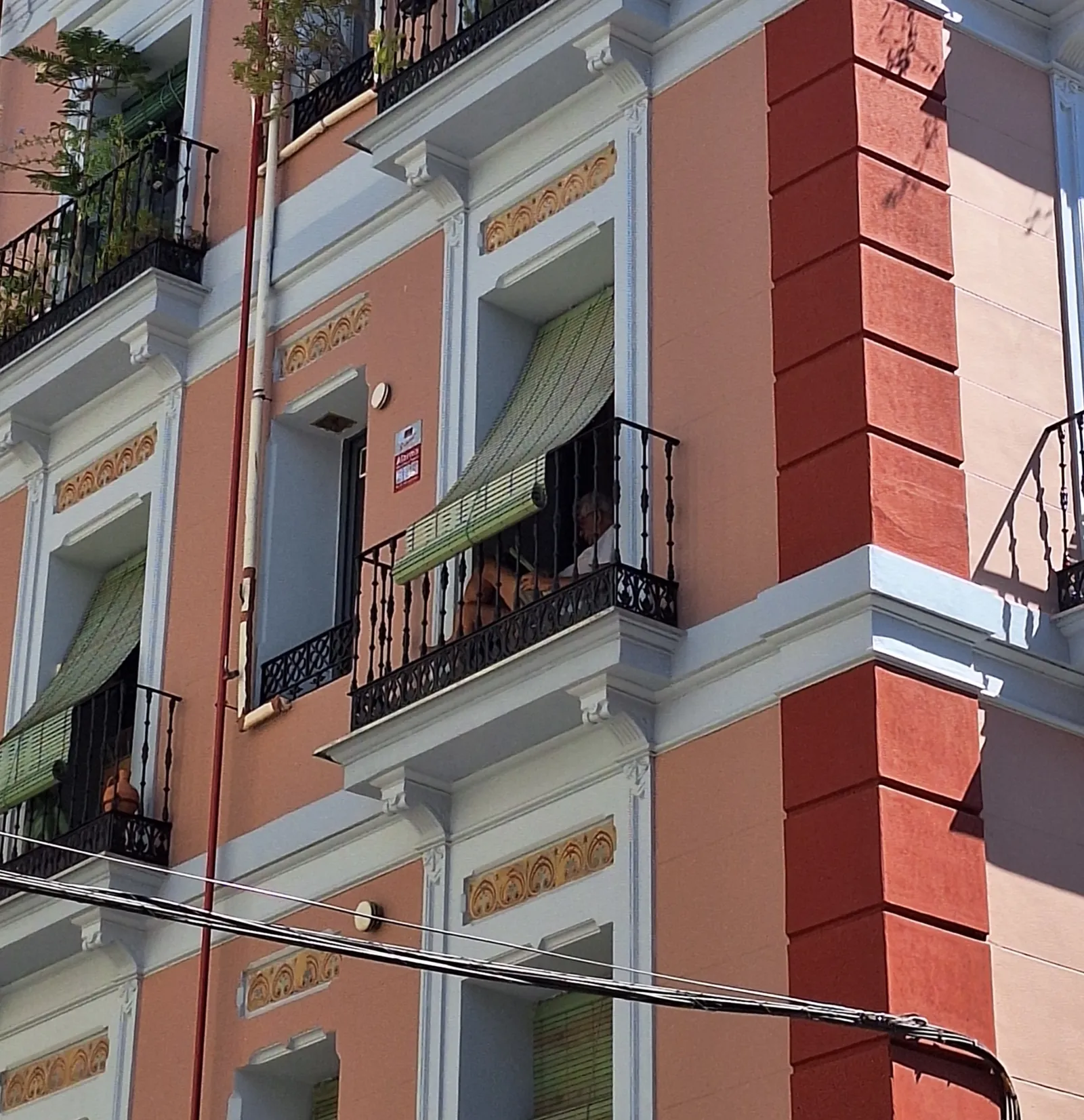 Balcones con contraventanas de madera y rejería en una fachada de Madrid