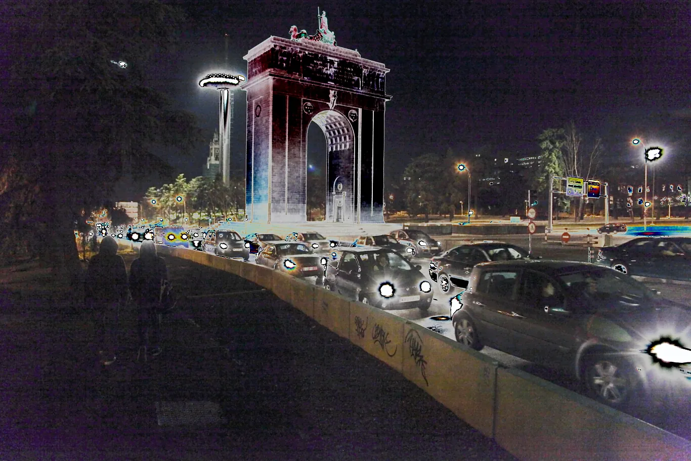El Arco de la Victoria de Madrid iluminado de noche, con coches en la carretera