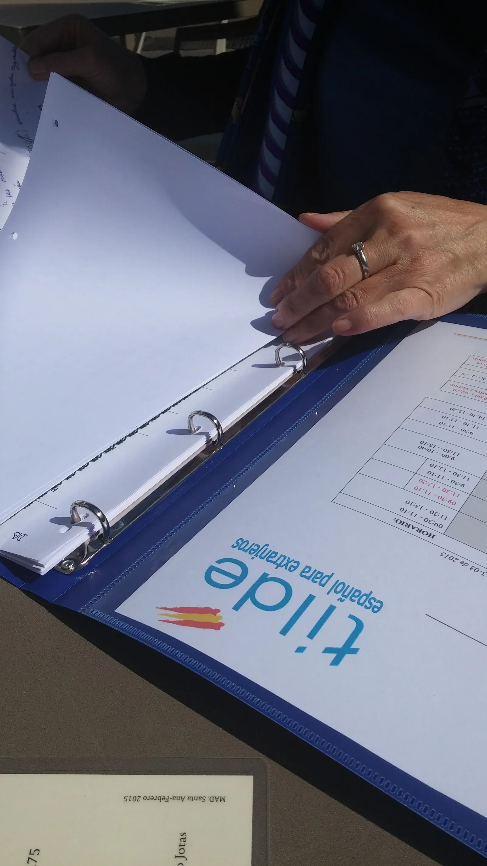 Manos pasando las hojas de una carpeta de la escuela Tilde