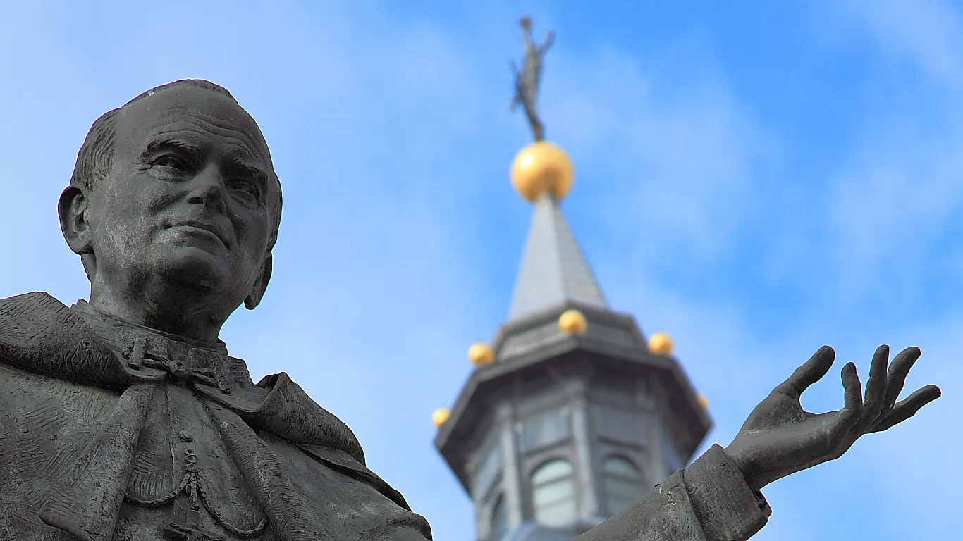 Estatua de bronce de Juan Pablo II con una torre de la catedral de la Almudena al fondo